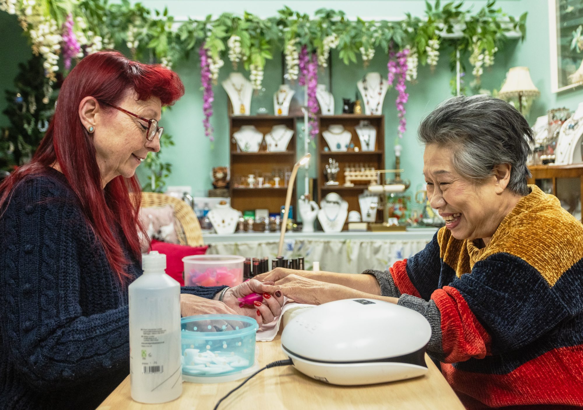 Two people laughing while getting a manicure