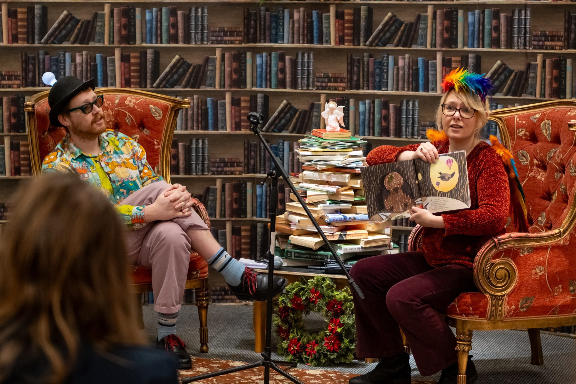 Two people in colourful outfits sitting in chairs during a book reading at Sparks