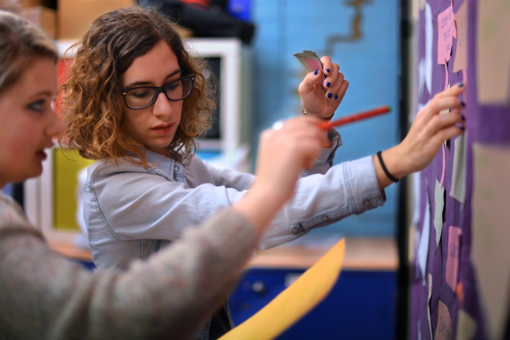 2 people sticking postit notes on a wall
