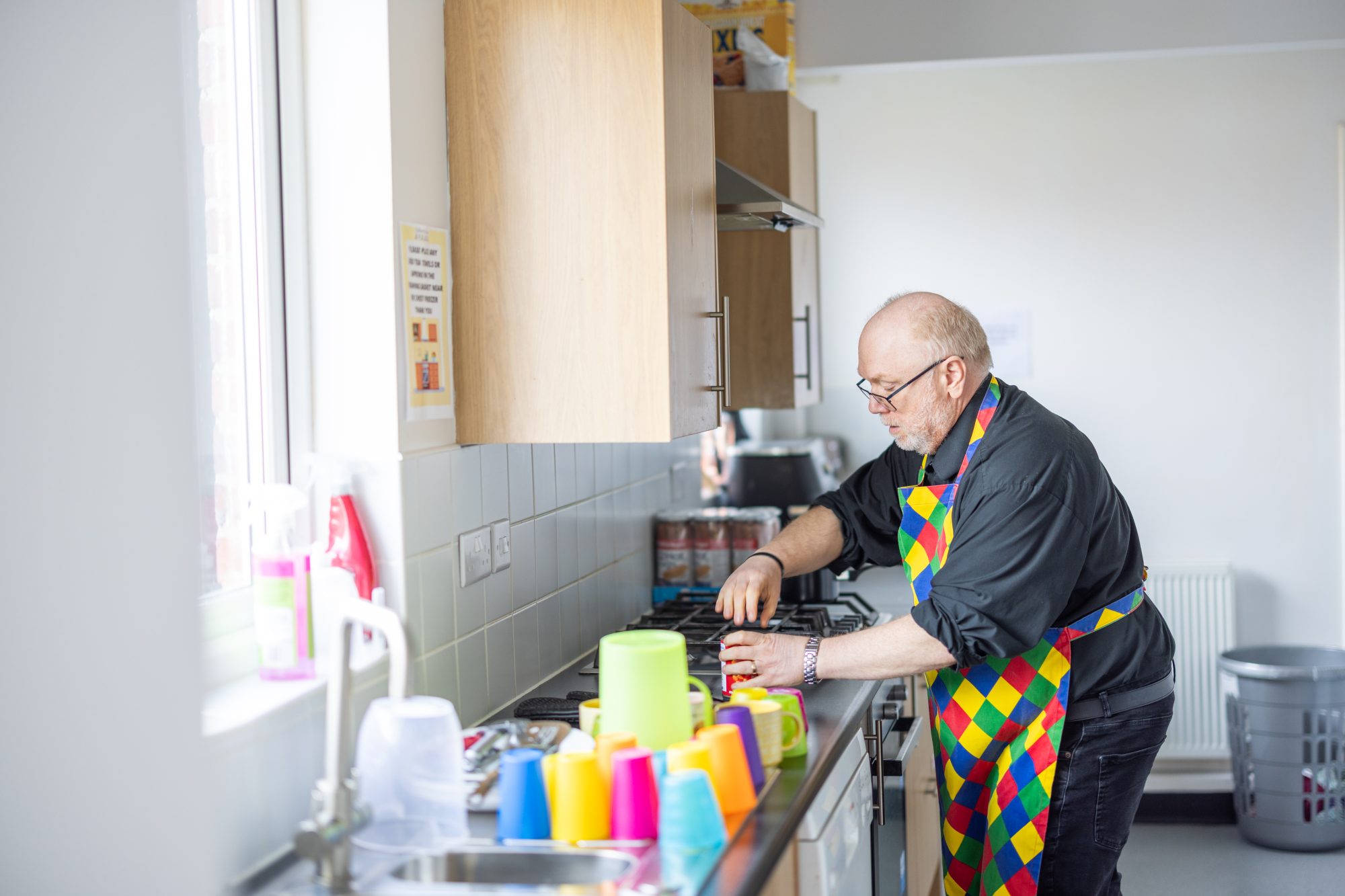 2025_NE Edberts House Gavin Forster Photography-7566 A man in a colorful apron preparing food in a kitchen at Edberts House
